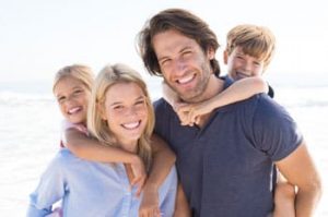 Family photo with two smiling parents and a young boy and girl on their backs