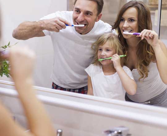 family brushing their teeth in front of mirror